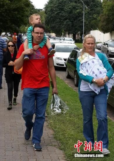 圖為一個(gè)白人家庭，由父母帶著孩子到曼德拉家門外悼念。中新社發(fā) 宋方燦 攝