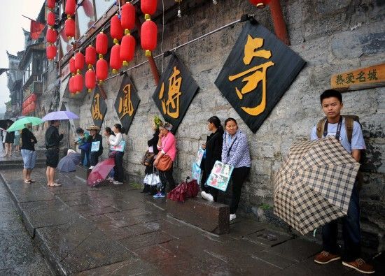 　4月29日上午11時(shí)20分，一些游客和古城當(dāng)?shù)氐木用穸阍谝粋€(gè)酒吧的屋檐下避雨。這些當(dāng)?shù)鼐用褚詾橛慰团恼罩\生，一場(chǎng)降雨讓他們的生意更加清淡。