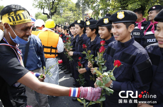 2013年12月03日,曼谷總理府與曼谷警署允許反政府示威民眾進入,雙方進入暫時“停戰(zhàn)”狀態(tài)迎接泰王生日。曼谷警察總署,女警們手持鮮花送給反政府示威民眾。圖片來源:Manish Swarup/東方IC