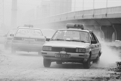 施工的道路上，車(chē)輛通過(guò)塵土飛揚(yáng)。